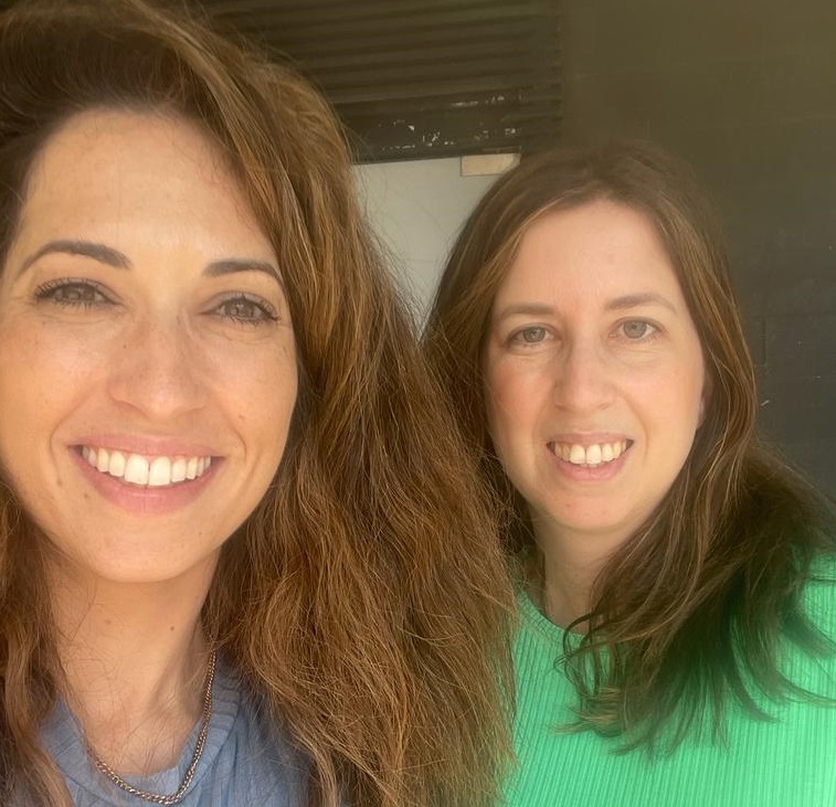 שתי נשים מחייכות אל המצלמה בצילום עצמי מקרוב, בחוץ ביום בהיר. שני וידרגורן משמאל, וד"ר מעיין בוימן משיטה מימין בחולצה ירוקה.